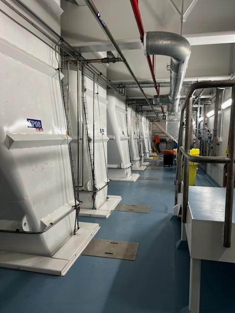 Mechanical room with large HVAC units and ducting laid out for inspection, labeling, and access checks.