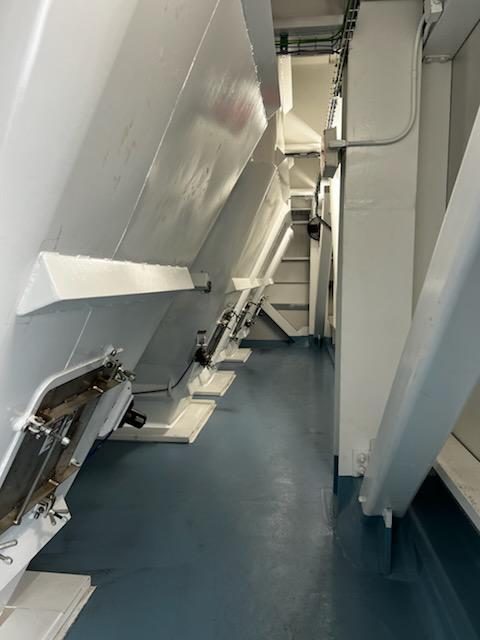 Wide interior view of a clean industrial facility featuring multiple large white sloped components along a blue floor, showcasing a professional workspace maintained for NDT field services.